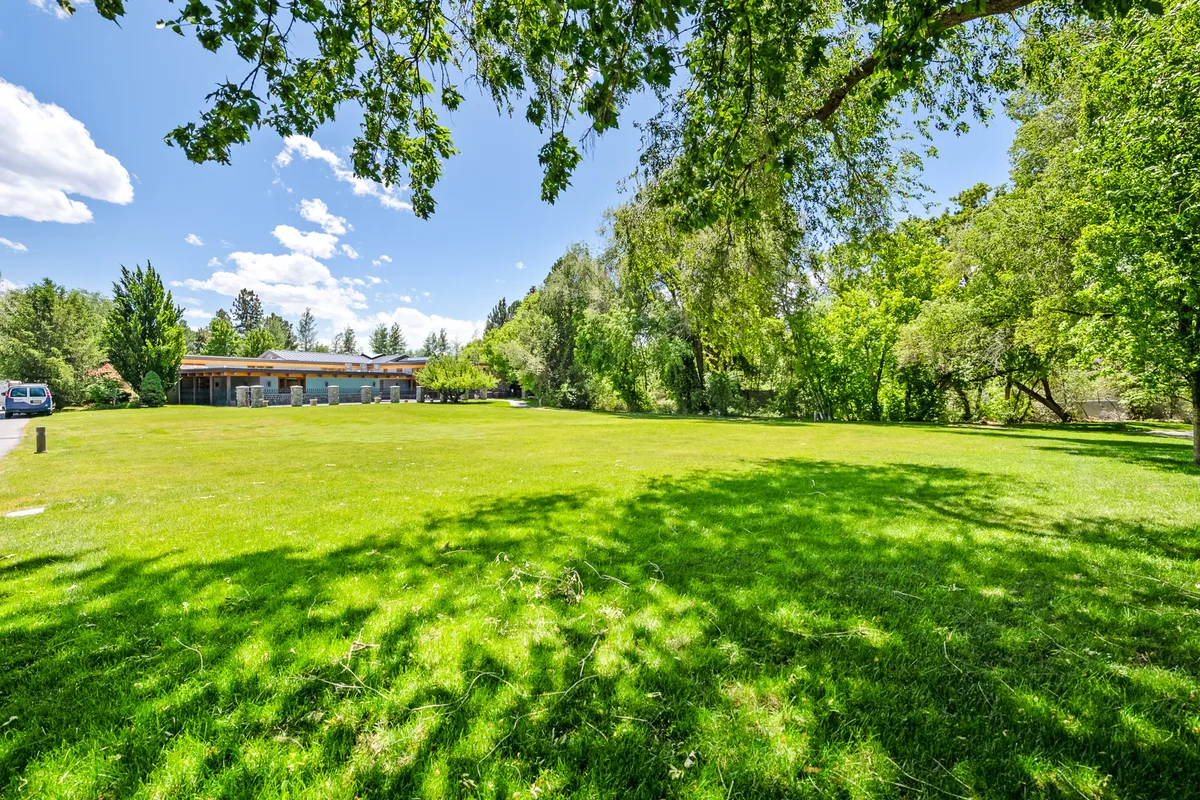 Open lawn and mature trees at the undeveloped home site