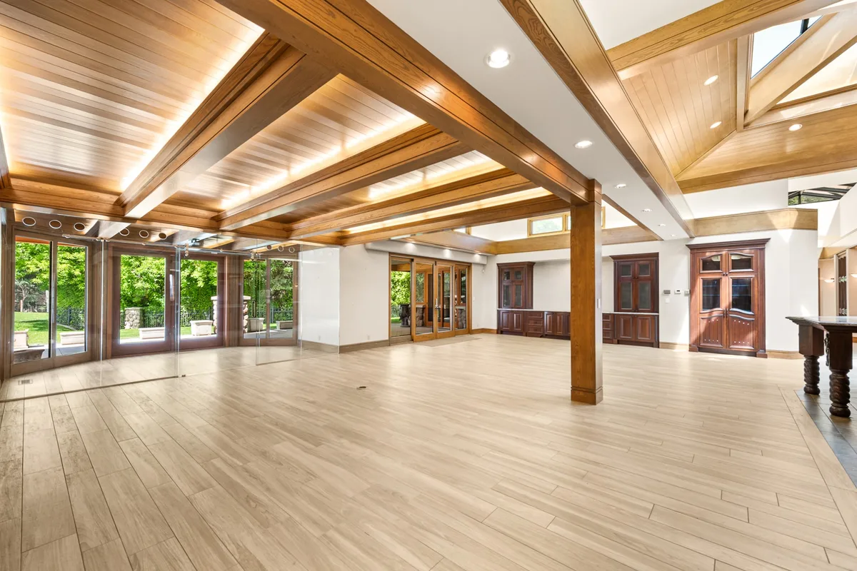 Open interior with warm wood ceiling beams and broad garden windows