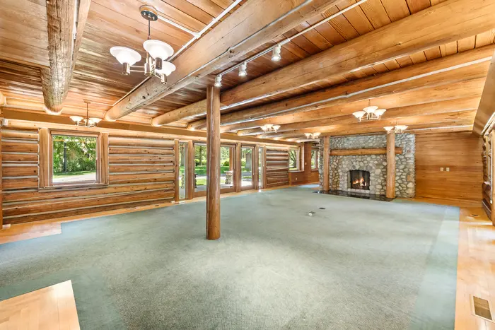 Cabin great room with log walls and stone fireplace